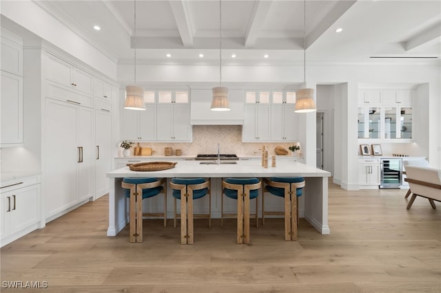 kitchen with a breakfast bar area, beverage cooler, light countertops, tasteful backsplash, and beamed ceiling