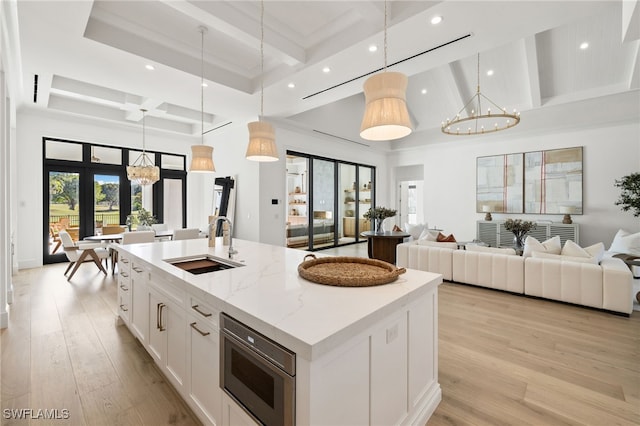 kitchen with light wood-style floors, a sink, and beamed ceiling