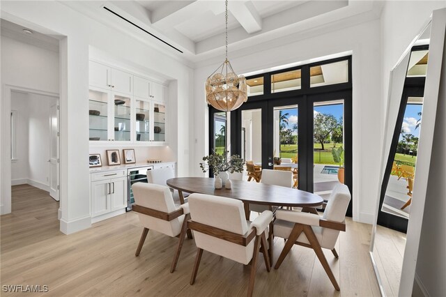 dining room featuring wine cooler, light wood finished floors, a high ceiling, coffered ceiling, and baseboards