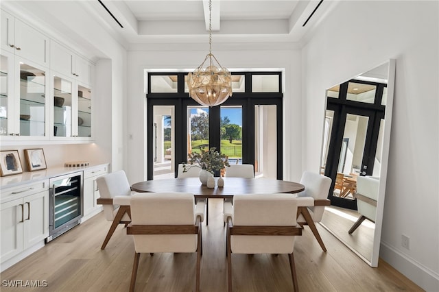 dining room featuring beverage cooler, french doors, light wood-type flooring, and a towering ceiling