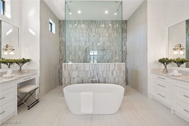 full bathroom with a walk in shower, a soaking tub, vanity, and tile walls