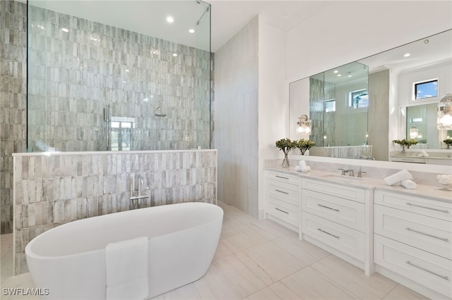 bathroom with walk in shower, a freestanding bath, vanity, tile walls, and recessed lighting