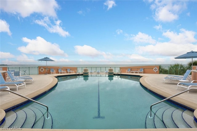 pool featuring a patio area, fence, and a water view