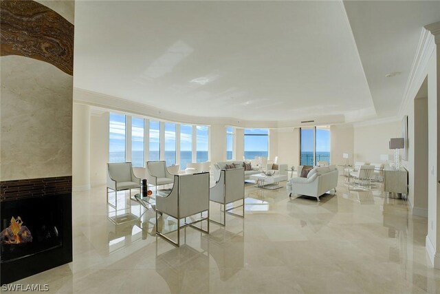 tiled living room featuring a water view, crown molding, and a high end fireplace