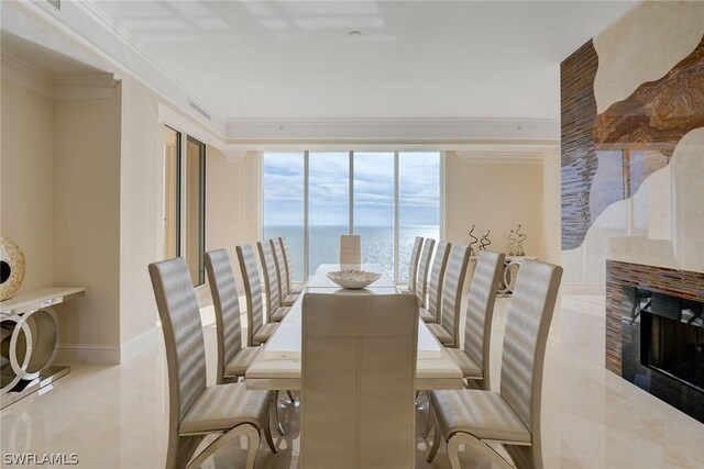 dining space with a water view, a fireplace, and crown molding