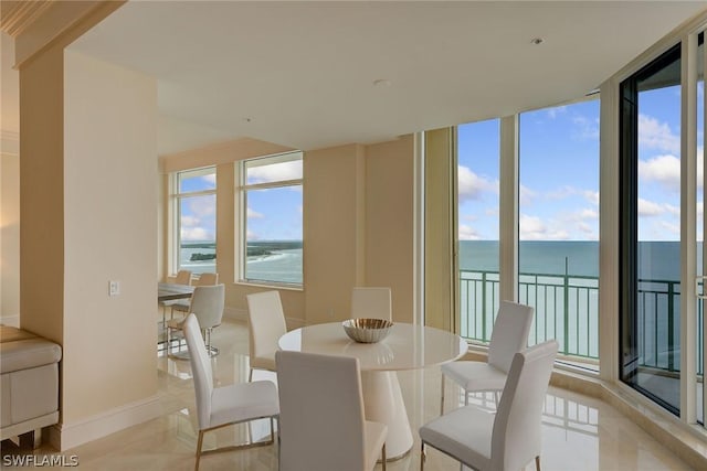 dining room featuring plenty of natural light, a wall of windows, a water view, and baseboards