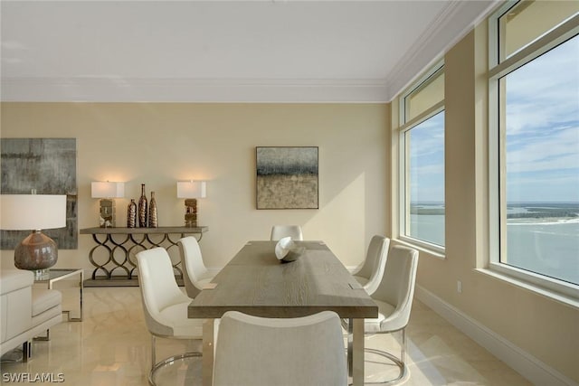 dining room featuring ornamental molding, a water view, and baseboards