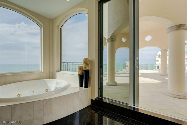 bathroom featuring a water view, decorative columns, and plenty of natural light