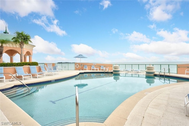 community pool with a patio, a water view, and fence