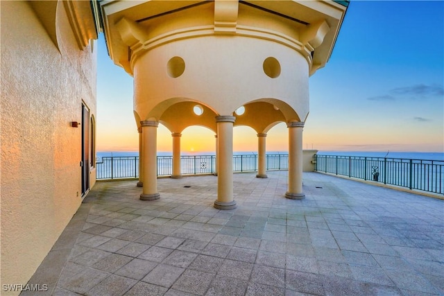 patio terrace at dusk featuring a water view