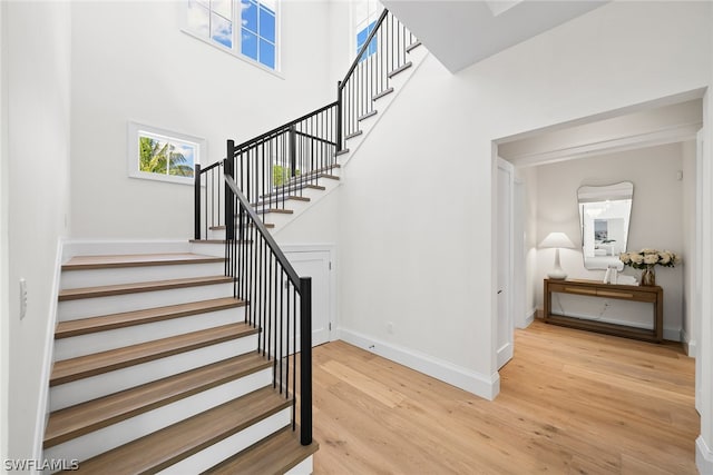 stairs featuring light hardwood / wood-style flooring and a high ceiling