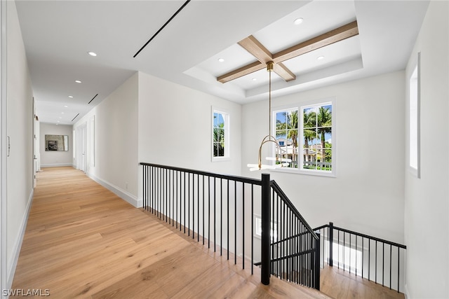 corridor with light hardwood / wood-style floors, beam ceiling, and coffered ceiling