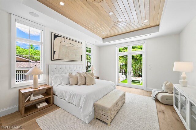 bedroom featuring wood ceiling, light hardwood / wood-style floors, access to outside, and a tray ceiling