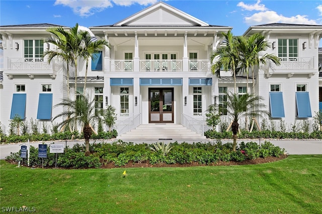 exterior space featuring french doors, a balcony, and a front lawn