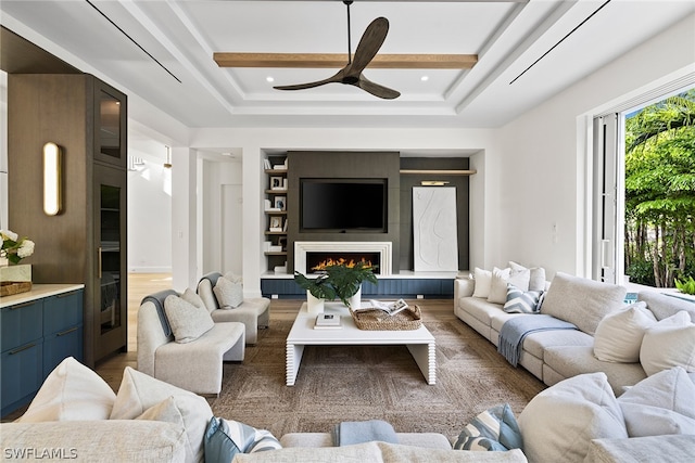 living room with wood-type flooring, a raised ceiling, and ceiling fan