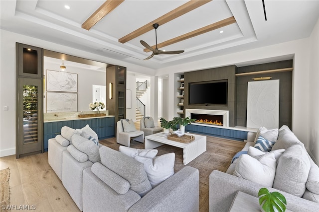 living room featuring light hardwood / wood-style flooring, beamed ceiling, ceiling fan, and a raised ceiling