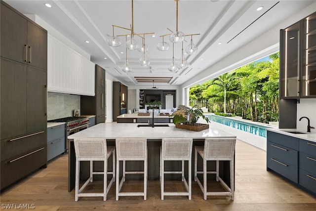 kitchen featuring a kitchen breakfast bar, light hardwood / wood-style floors, an island with sink, and white cabinetry