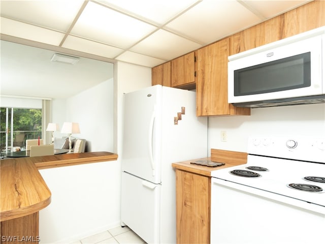 kitchen featuring white appliances, light tile patterned floors, and a drop ceiling