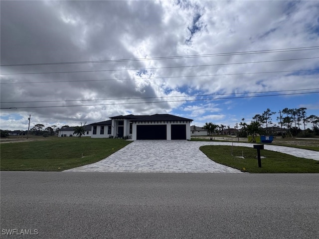 view of front of house featuring an attached garage, decorative driveway, and a front lawn