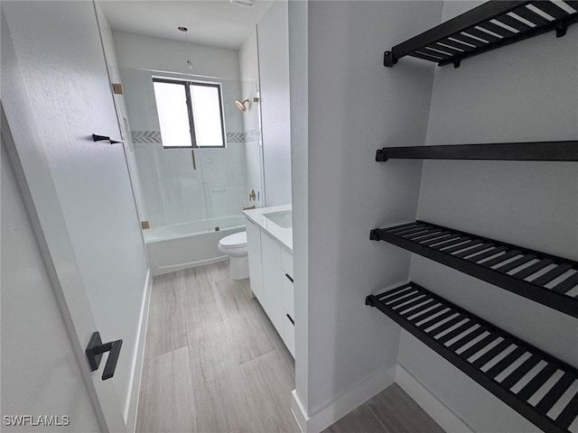 bathroom with vanity, wood finished floors, baseboards,  shower combination, and toilet