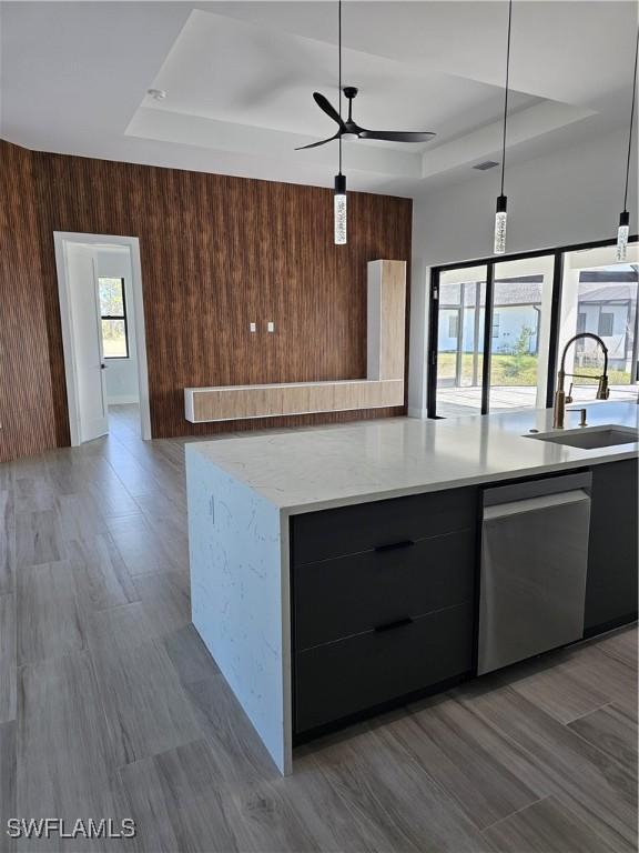 kitchen with stainless steel dishwasher, a raised ceiling, modern cabinets, and a sink