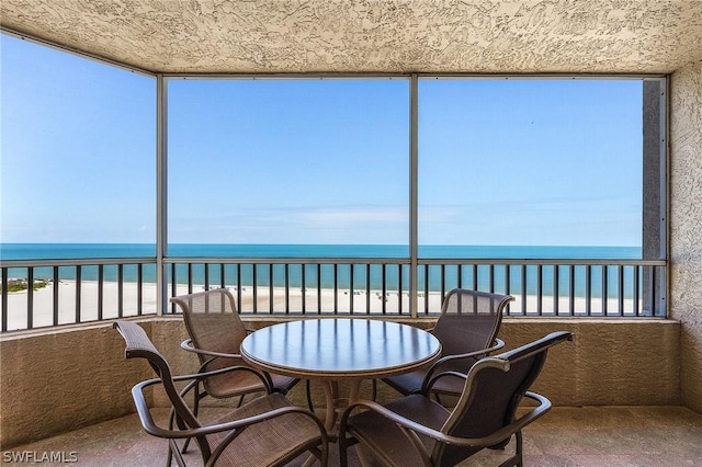 sunroom / solarium featuring a beach view and a water view