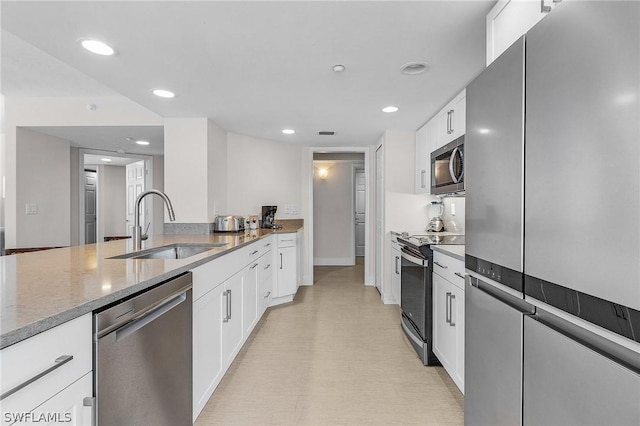 kitchen featuring sink, white cabinetry, light stone counters, and appliances with stainless steel finishes