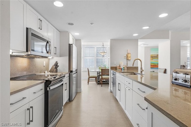 kitchen featuring light stone counters, decorative backsplash, white cabinetry, appliances with stainless steel finishes, and sink