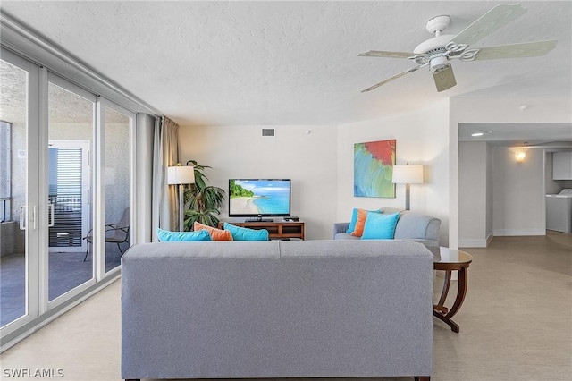 living room with a textured ceiling, ceiling fan, a healthy amount of sunlight, and washer / clothes dryer