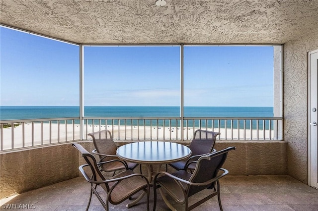 sunroom featuring a water view and a view of the beach