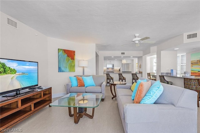 living room with a textured ceiling and ceiling fan