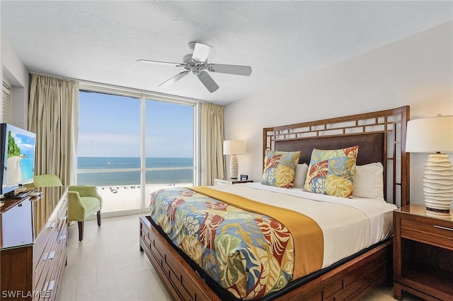 bedroom featuring ceiling fan, expansive windows, and a water view