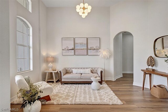 sitting room with hardwood / wood-style floors, a towering ceiling, and an inviting chandelier