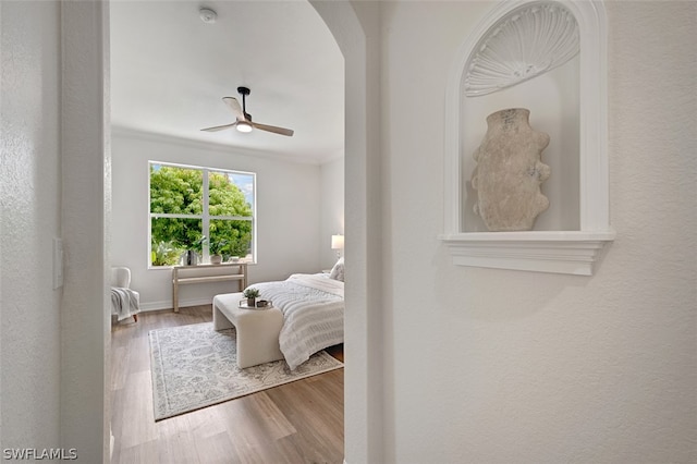 bedroom with ceiling fan, wood-type flooring, and ornamental molding