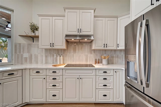 kitchen with white cabinets, stainless steel fridge, light wood-type flooring, and black electric cooktop