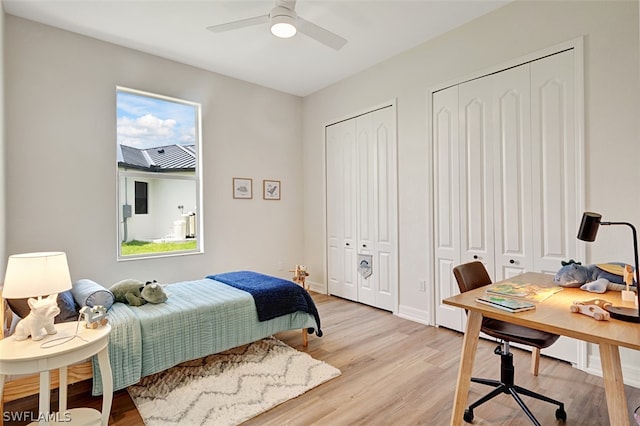 bedroom with light wood-type flooring, two closets, and ceiling fan