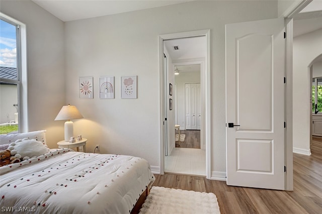 bedroom featuring connected bathroom and light hardwood / wood-style floors