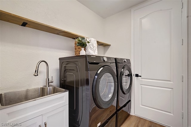 washroom with washing machine and dryer, sink, cabinets, and light hardwood / wood-style floors