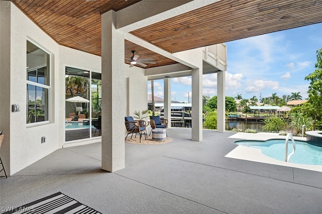 view of pool with ceiling fan, a water view, and a patio