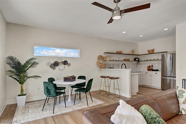 dining area with ceiling fan, light hardwood / wood-style flooring, and sink