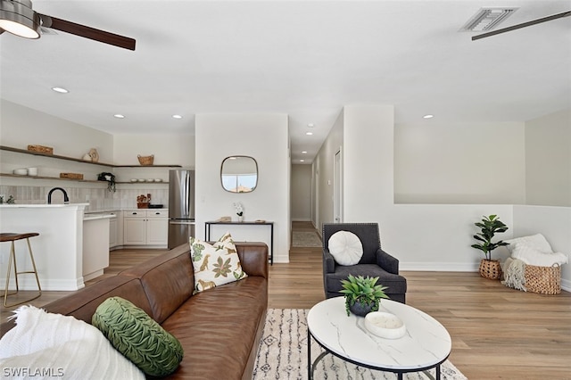 living room with light hardwood / wood-style flooring, ceiling fan, and sink