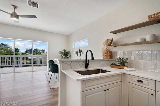 kitchen featuring ceiling fan, white cabinetry, sink, and light hardwood / wood-style flooring