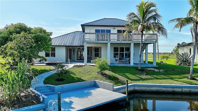 rear view of property with a patio, a balcony, and a lawn