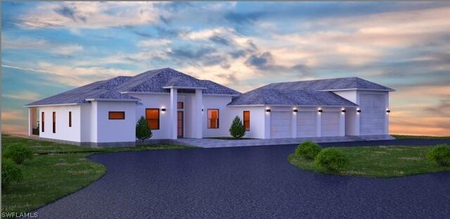 view of front of home featuring driveway, an attached garage, and stucco siding