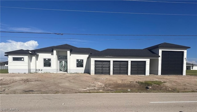 prairie-style house featuring a garage, dirt driveway, and stucco siding