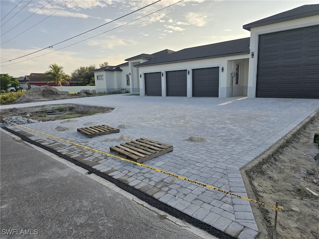 view of front of house featuring decorative driveway, an attached garage, and stucco siding