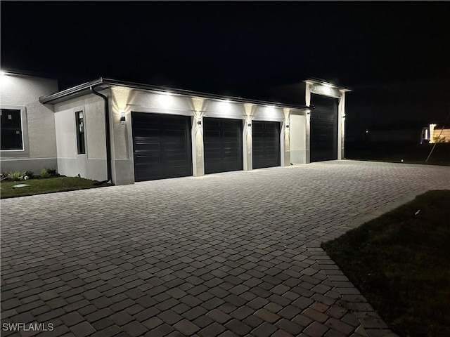 garage at twilight featuring decorative driveway