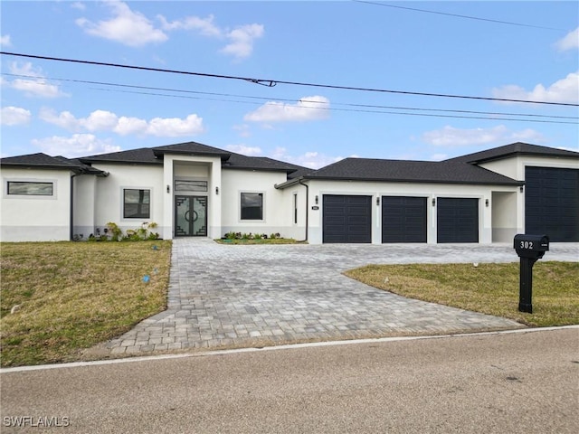 prairie-style home featuring an attached garage, decorative driveway, a front yard, and stucco siding