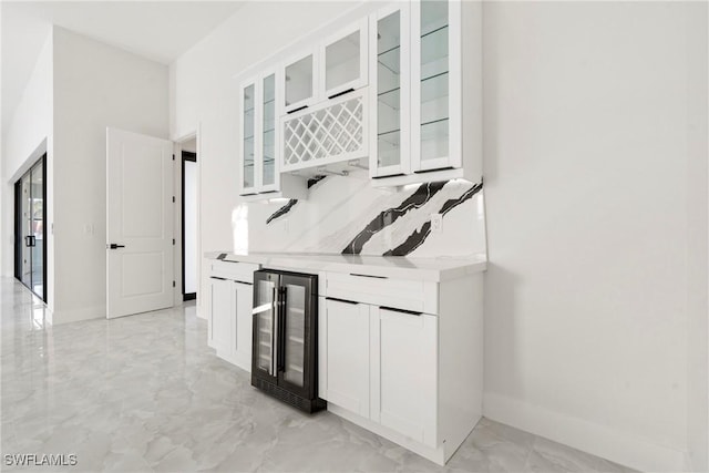 bar featuring a dry bar, baseboards, decorative backsplash, wine cooler, and marble finish floor