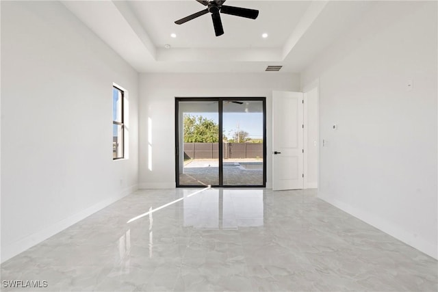 spare room featuring marble finish floor, visible vents, a tray ceiling, and baseboards